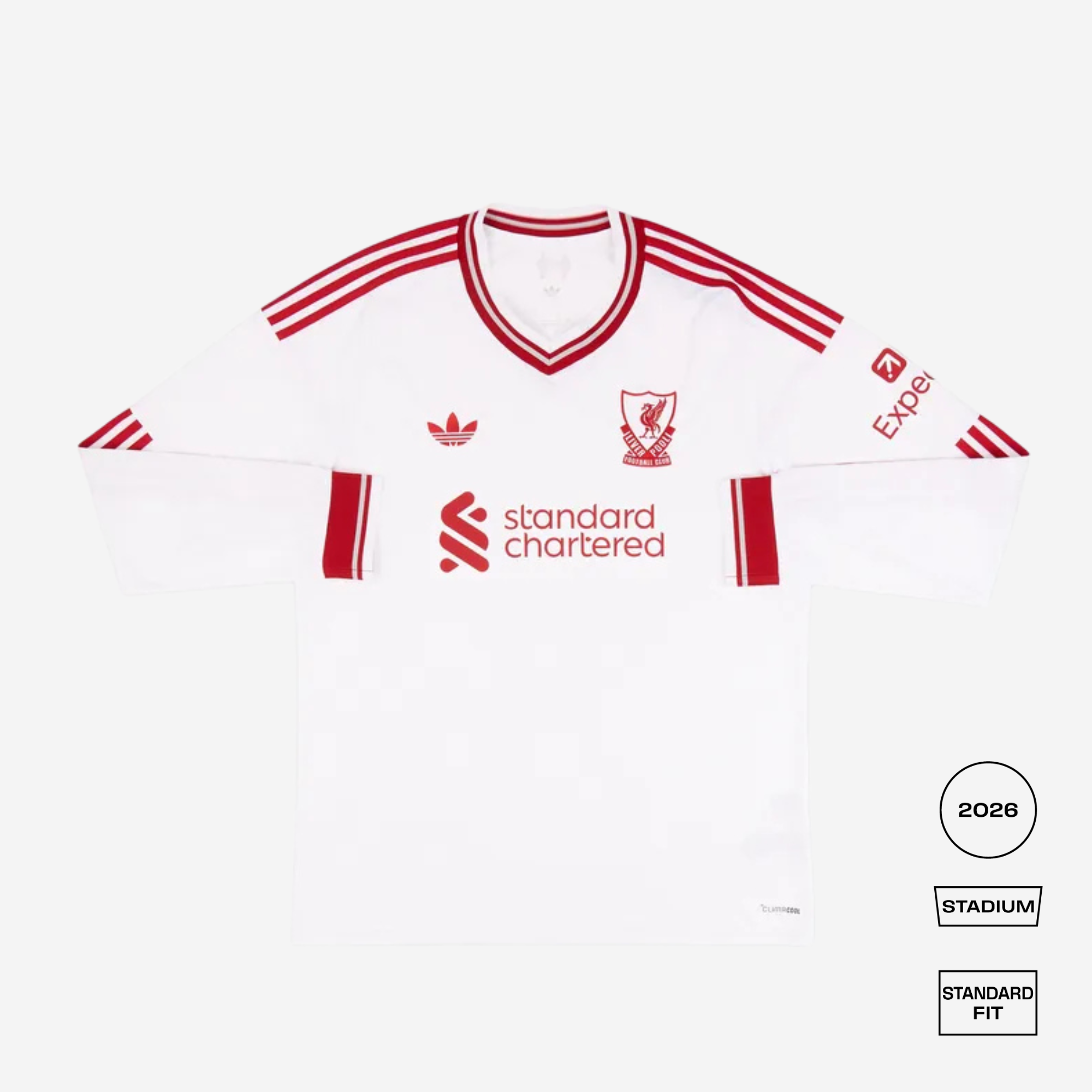 A white long-sleeve football jersey with red stripes and red printed logos, laid flat on a light gray background. Visible branding includes the Liverpool crest, Adidas logo, Experi sponsor logo, and Standard Chartered sponsor logo.