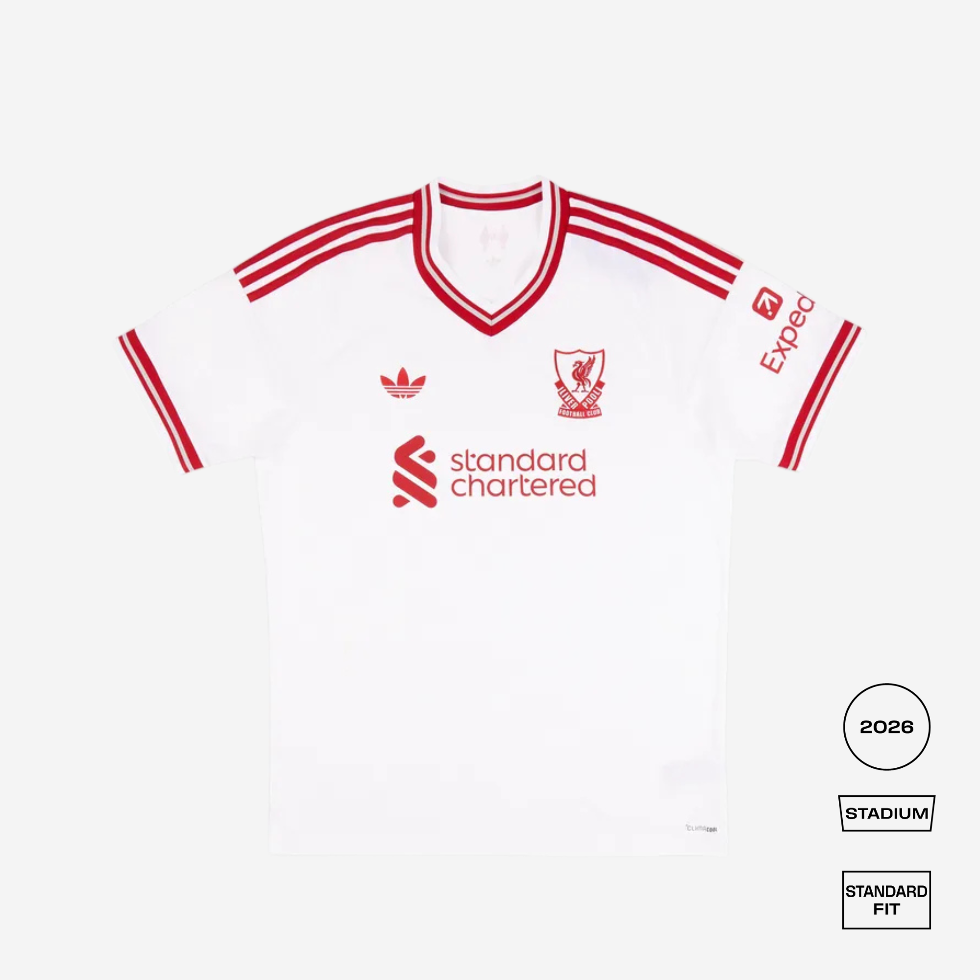 A white Liverpool football jersey with red stripes and logos, laid flat on a light gray background. The jersey features the Adidas logo, Liverpool crest, Standard Chartered sponsor logo, and Exceq sleeve logo.