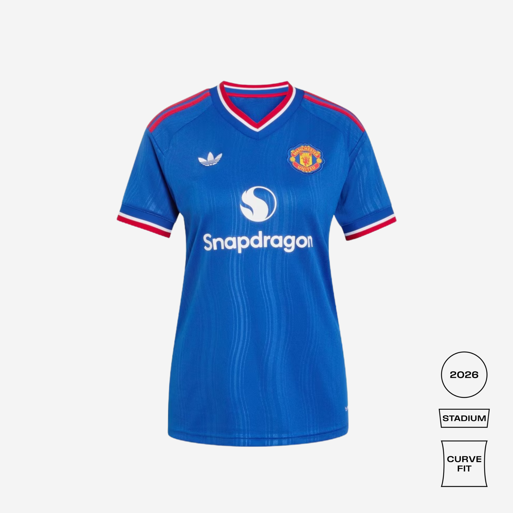 A blue short-sleeve soccer jersey with red and white trim on the collar and sleeves, featuring the Manchester United crest and Snapdragon sponsor logo on a light gray background. Three small fit/edition badges appear on the bottom right.