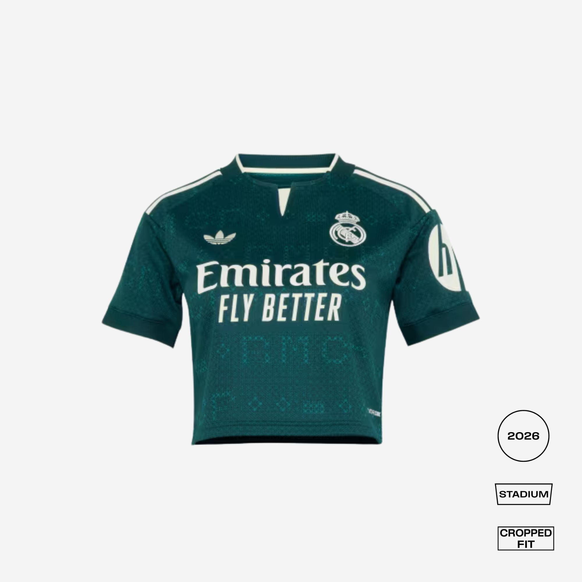 A dark green Real Madrid 2026 Stadium cropped fit soccer jersey by Adidas, featuring white sponsor and team logos, displayed on a light gray background with fit/style badges.