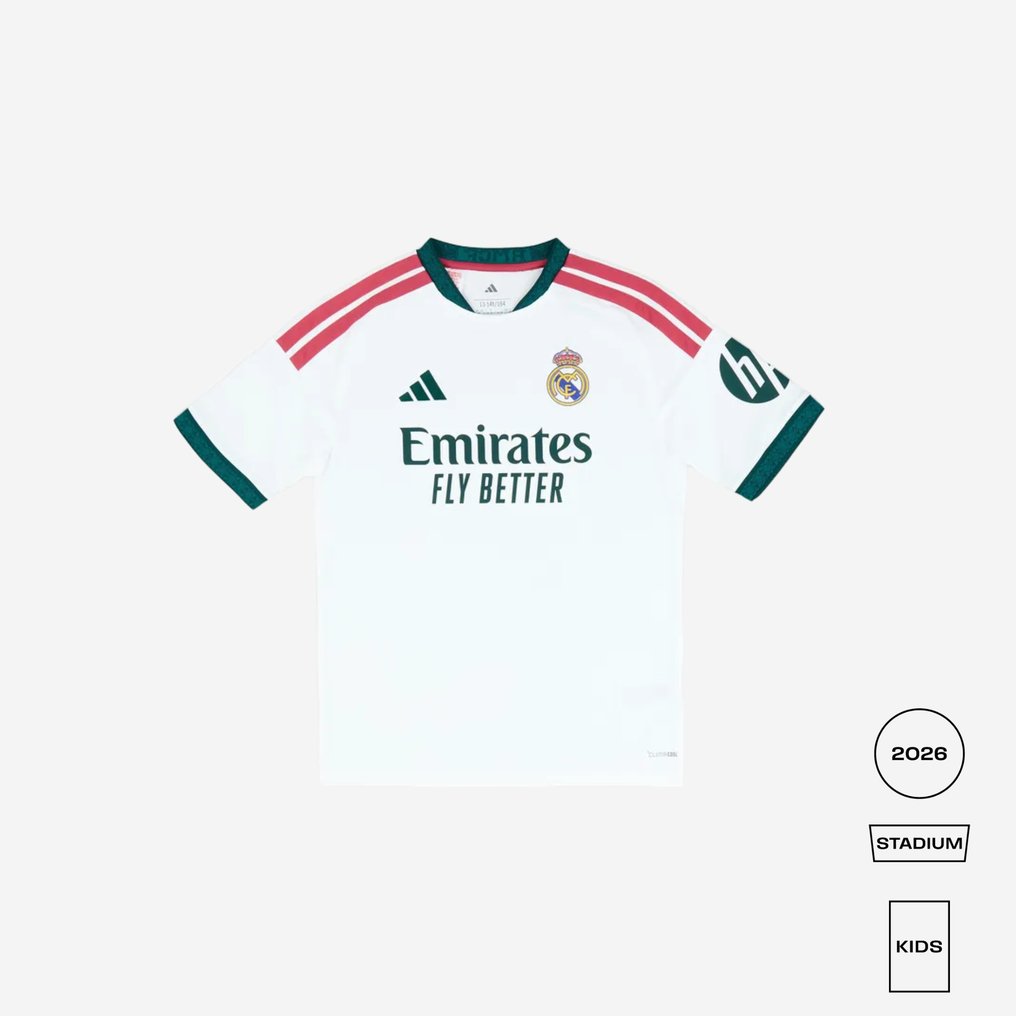 A white Real Madrid 2026 Stadium Kids soccer jersey by adidas, featuring green and red shoulder stripes, green trim on the collar and cuffs, the Emirates Fly Better sponsor logo, and the club crest on the chest.