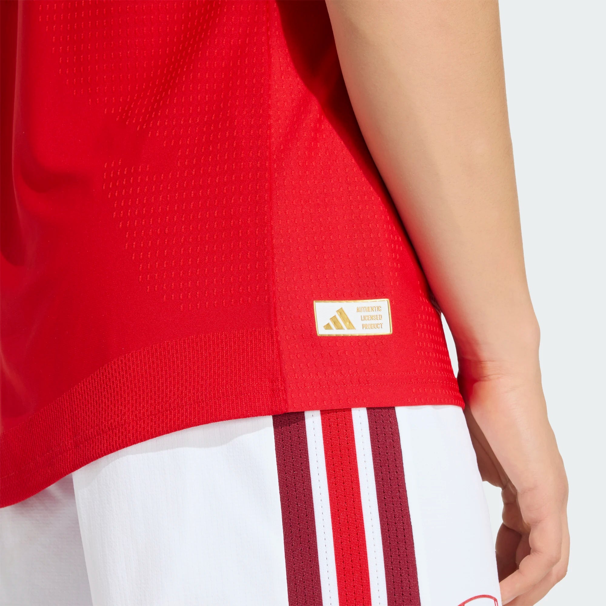 Red sports jersey with Adidas logo and white shorts with red stripes on a white background