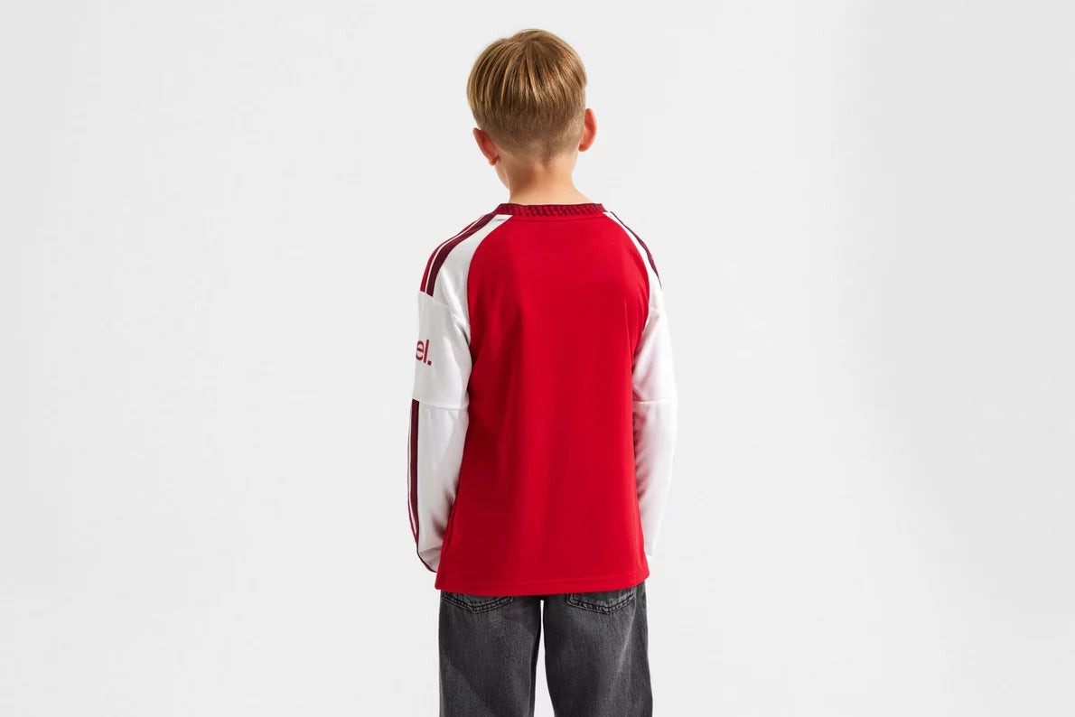 Child wearing a red and white sports jersey on a plain background