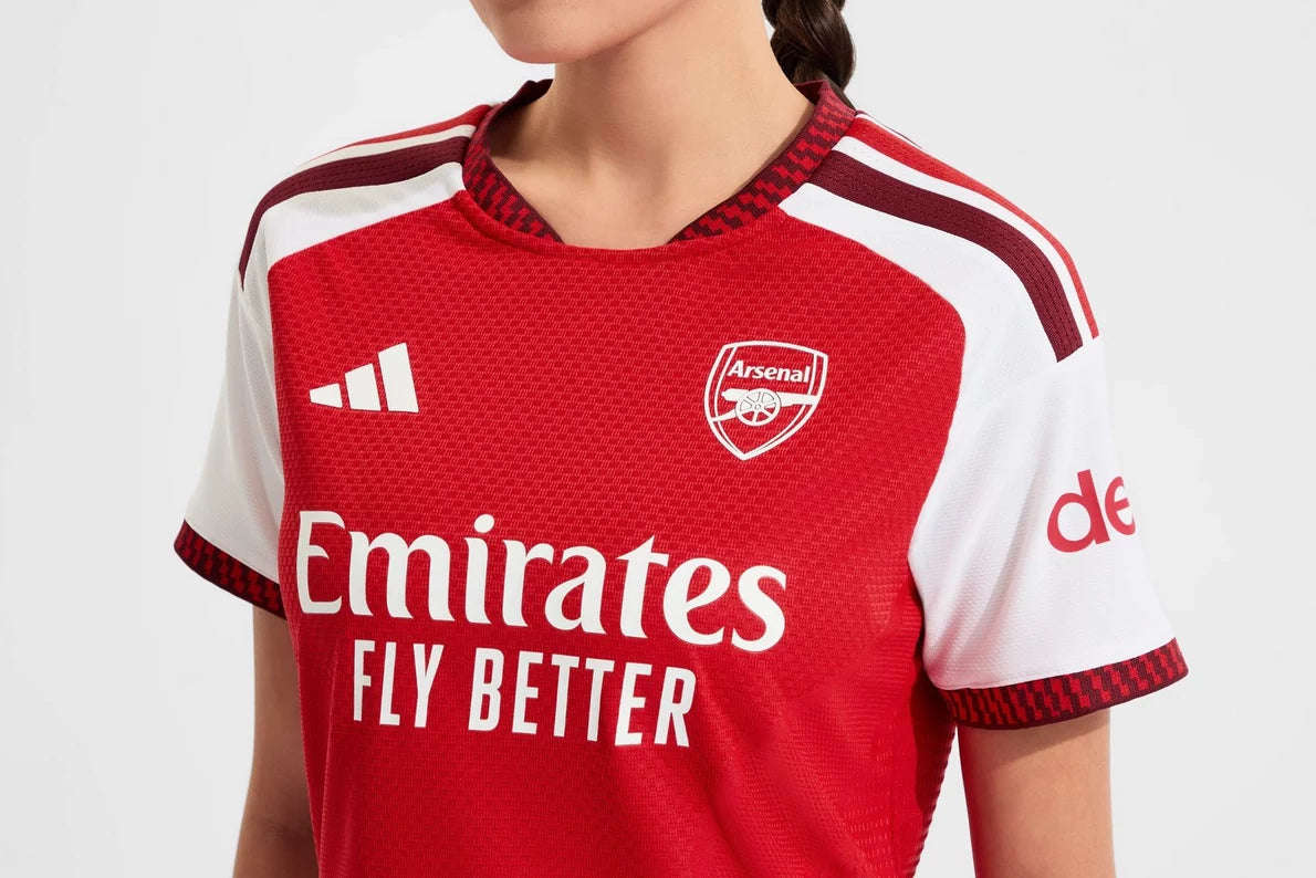 Red and white sports jersey with Arsenal logo and Emirates branding on a white background