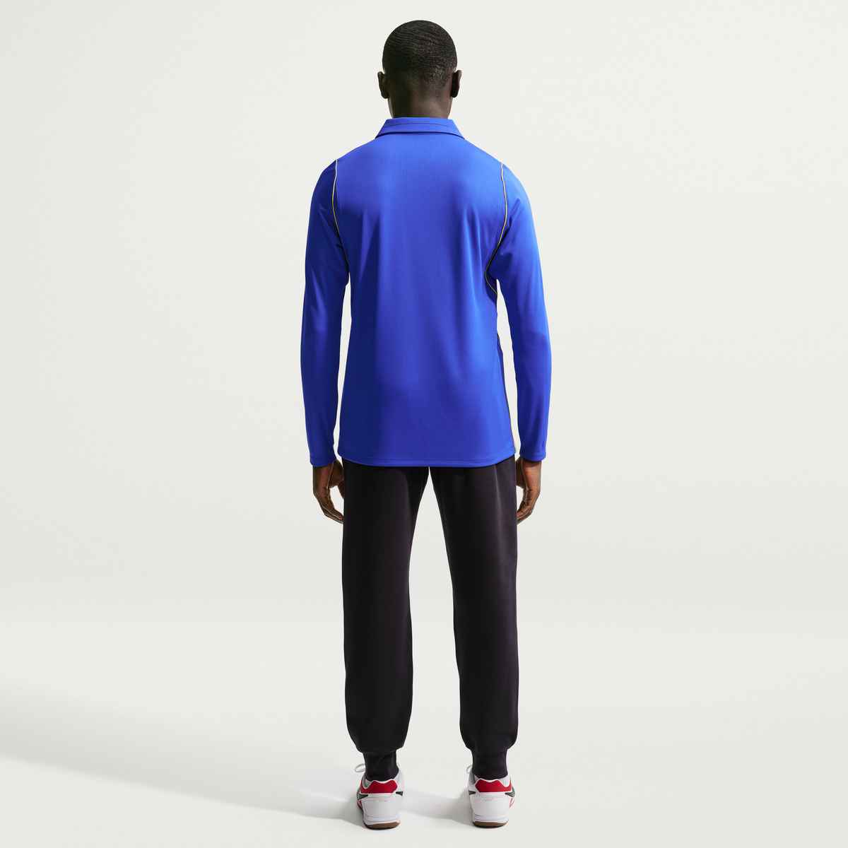 Person wearing a blue long-sleeve shirt and black pants on a white background