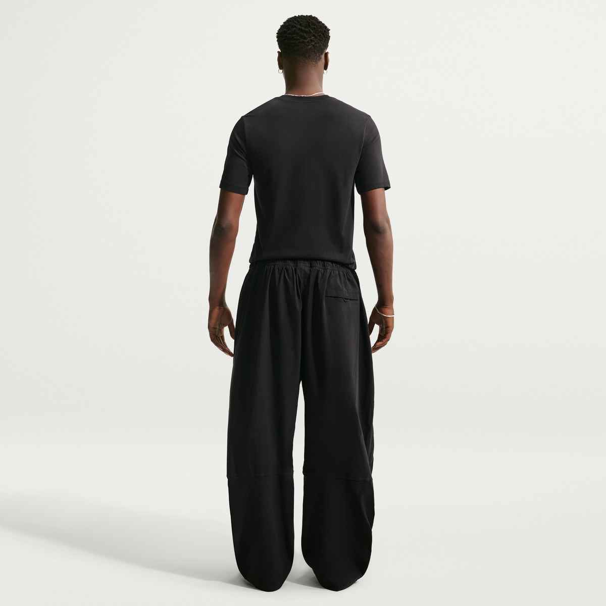 Person wearing a black t-shirt and wide-leg pants on a white background
