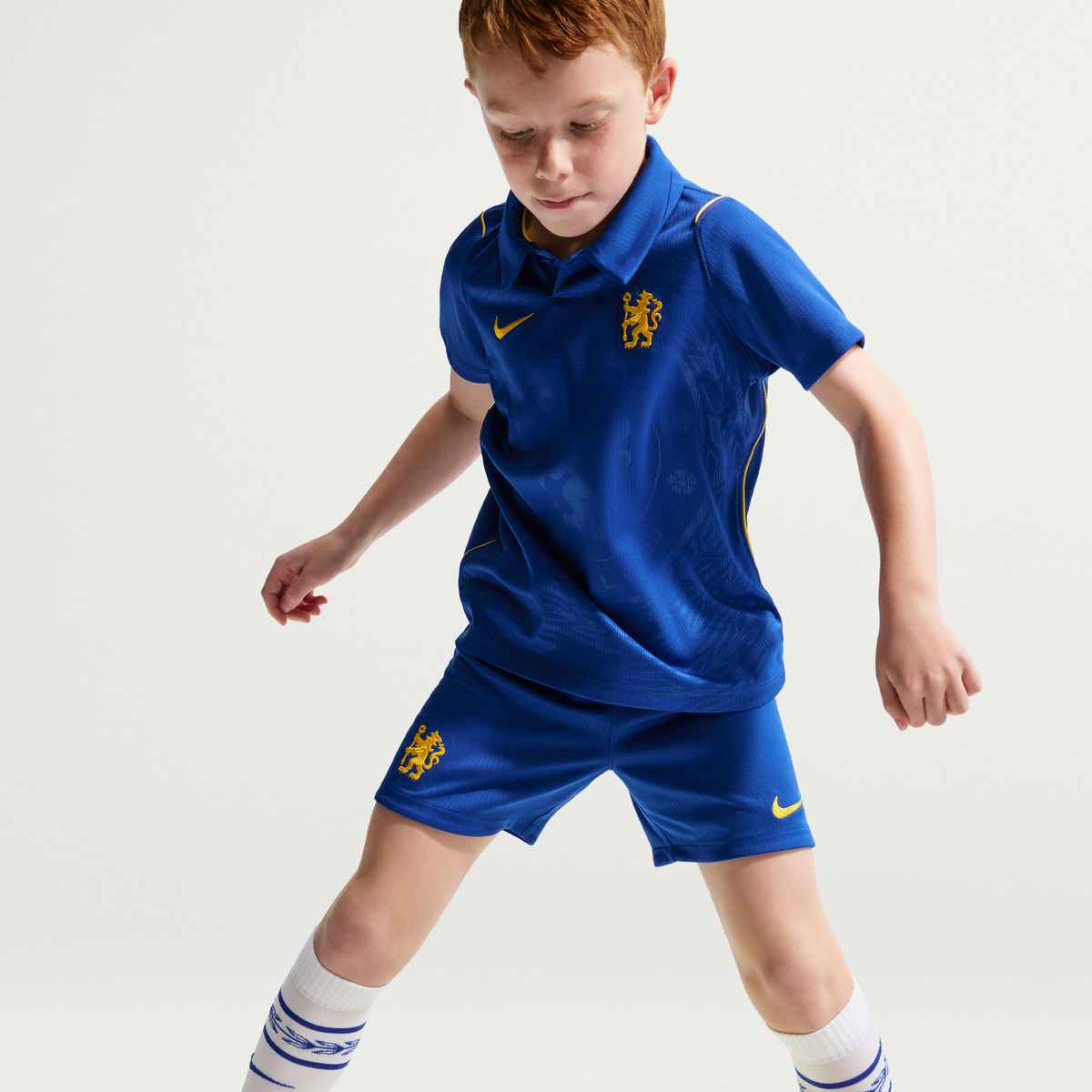 Child wearing a blue sports outfit with lion emblem on a light gray background