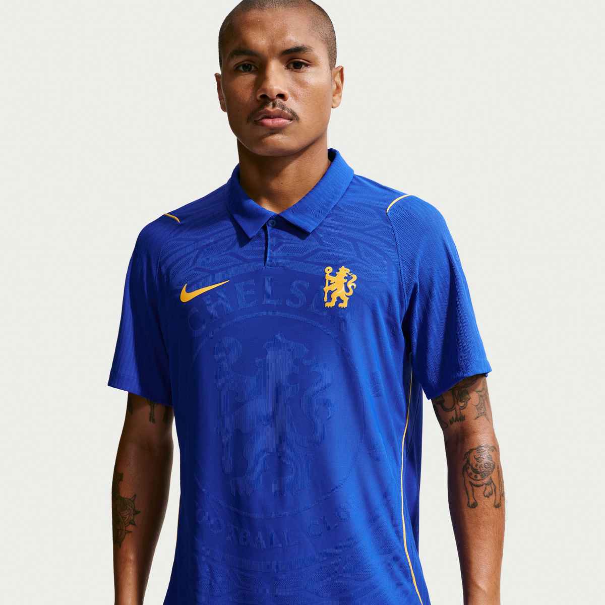 Person wearing a blue sports jersey with a logo on a light gray background